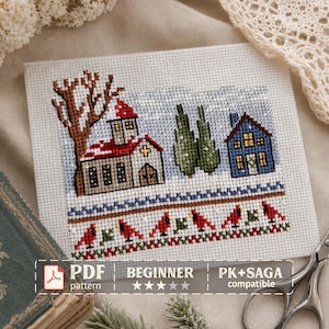 May include: A cross-stitch pattern on white Aida fabric featuring a winter scene with a church, a blue house, two green trees, and a row of red cardinals. The text reads PDF BEGINNER PK+SAGA compatible. The design includes a brown tree and snow.