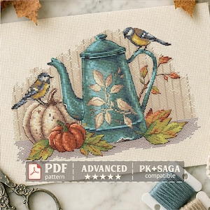 May include: A cross-stitch pattern on fabric featuring a teal teapot decorated with leaf motifs, two small birds, and two pumpkins surrounded by autumn leaves. The text reads PDF pattern, ADVANCED, and PK+SAGA compatible.