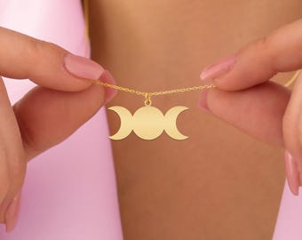 May include: A gold necklace with a triple moon pendant. The pendant is a simple design with three crescent moons.