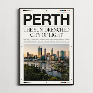 May include: A framed wall art print featuring a newspaper-style layout with the bold black text PERTH THE SUN-DRENCHED CITY OF LIGHT. Below the text is a colour photograph of the Perth skyline at sunset, reflecting over the Swan River.
