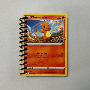 Cuaderno Pokémon de Charmander que utiliza una carta Pokémon genuina reutilizada de la serie Pokémon Go TCG e incluye 40 páginas en blanco para escribir.