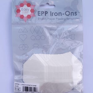 May include: A pack of 100 white 1-inch honeycomb-shaped paper piecing templates for English Paper Piecing. The pack is labelled "EPP Iron-Ons" and "EPP08 - 1 INCH HONEYCOMB X100".