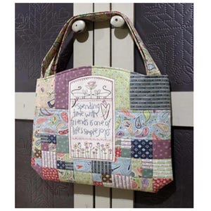 May include: A patchwork tote bag in various fabric patterns of purple, green, blue, and red. The bag has a rectangular panel with the embroidered text "Spending time with friends is one of life's simple joys."