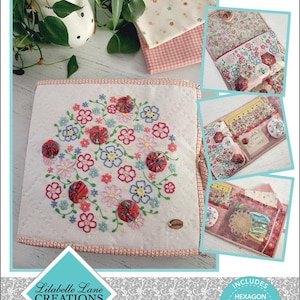 May include: A project folder with the text "Take Me There" and floral embroidery. The folder includes sewing supplies and templates. The design features a floral pattern with red, pink, and blue accents. The folder is labelled "Lilabelle Lane Creations."