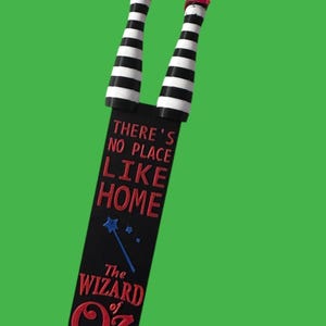 Wicked Witch Legs - striped black and white with Red Ruby Slippers.  Attached  to a bookmark reading " There's no place like home The Wizard of OZ"