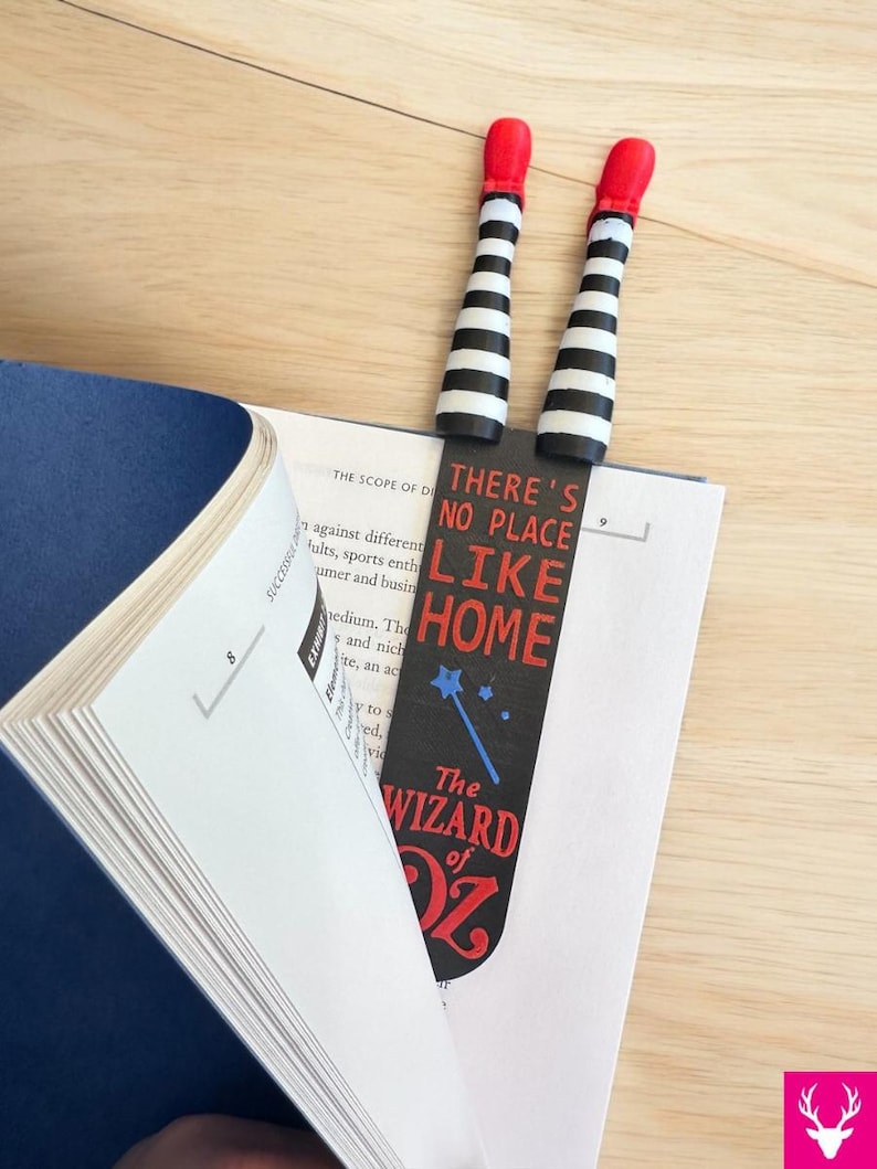 Wicked Witch Legs - striped black and white with Red Ruby Slippers.  Attached  to a bookmark reading " There's no place like home The Wizard of OZ"  The bookmark is placed in a book for display