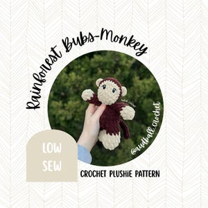 May include: A handmade crochet monkey plushie in burgundy and cream colors. The plushie is held in front of a green background. Text on the image reads "Rainforest Bubs-Monkey", "Low Sew", and "Crochet Plushie Pattern".
