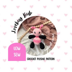 May include: A crocheted plushie lovebug in pink, black, and white. The lovebug has a pink body, black legs, and white wings. The image includes the text "Lovebug Bub", "Low Sew", and "Crochet Plushie Pattern".
