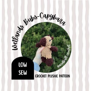 May include: A crochet plushie pattern for a capybara. The plushie is brown and tan, with dark brown accents. The text "Wetlands Bubs-Capybara" and "Low Sew" are visible. The words "Crochet Plushie Pattern" are also displayed.