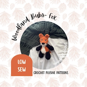 May include: A crocheted fox plushie with orange, white, and black details. The fox is set against a green blanket and white fabric. The text "Woodland Bubs- Fox" and "LOW SEW" are visible, along with "CROCHET PLUSHIE PATTERNS".