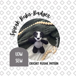 Könnte beinhalten: Ein gehäkeltes Dachs-Plüschtier in Schwarz, Weiß und Grau, mit dem Text "Squeak Bubs-Badger" und "LOW SEW" auf dem Bild. Das Plüschtier liegt auf einer dunkelgrünen Decke und einer weißen Oberfläche. Die Worte "CROCHET PLUSHIE PATTERN" sind ebenfalls sichtbar.