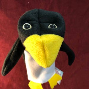 May include: Black and yellow penguin hand puppet with white belly and large black eyes.