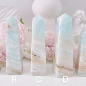 May include: Five blue and white crystal towers, labeled A through E, are arranged in a row on a white surface. The towers are all different sizes and shapes, with some having more white than blue and others having more blue than white.