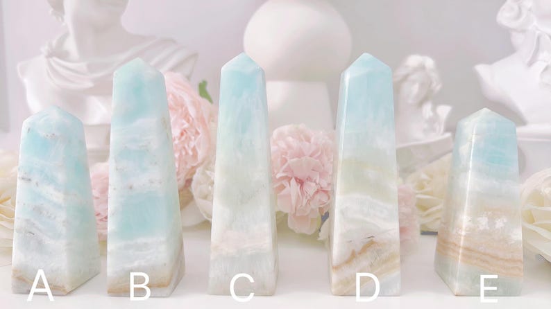 May include: Five blue and white banded crystal points labeled A through E. The points are arranged in a row on a white surface.