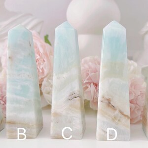 May include: Five light blue and white agate crystal points, labeled A through E. The points are arranged in a row on a white surface.