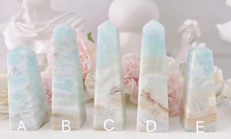 May include: Five light blue and white agate crystal points, labeled A through E. The points are arranged in a row on a white surface.