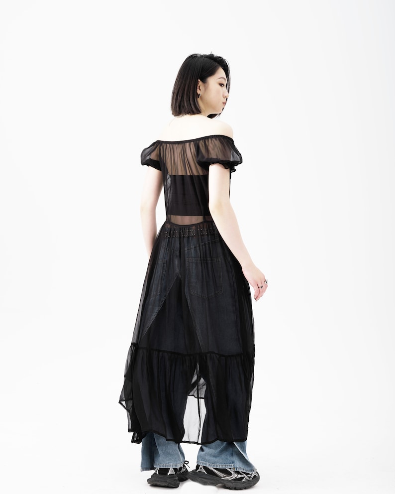 May include: A black sheer maxi dress with a ruffled hem and short puff sleeves. The dress is semi-transparent and has a fitted bodice.