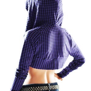 Puede incluir: Una sudadera con capucha corta de color morado y negro con un patr&oacute;n de pata de gallo. La sudadera tiene manga larga y capucha.