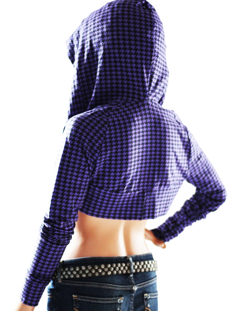 Puede incluir: Una sudadera con capucha corta de color morado y negro con un patr&oacute;n de pata de gallo. La sudadera tiene manga larga y capucha.