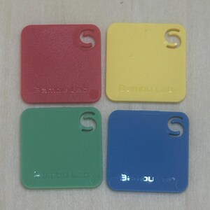 May include: Four square plastic samples in red, yellow, green, and blue. Each sample has a small "S" cut out of the top right corner and the text "Bamboo Lab" printed on the bottom.