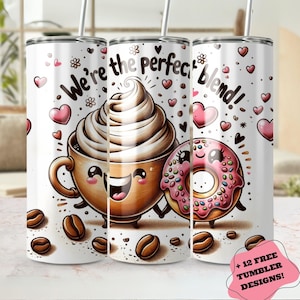 May include: A white tumbler featuring a cartoon illustration of a coffee cup and a donut. The coffee cup has whipped cream and a smiling face. The donut is pink with sprinkles and also has a smiling face. The text on the tumbler reads "We're the perfect blend!" and is surrounded by hearts and coffee beans.
