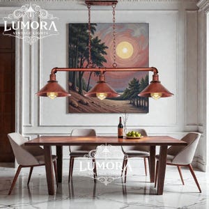May include: A three-light pendant lamp with copper shades and piping, suspended above a wooden dining table. The image features the text "LUMORA VINTAGE LIGHTS". The lamp is a vintage style.