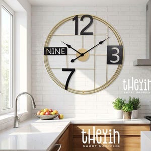 May include: A large, circular wall clock with a gold frame and black numerals. The clock face displays the numbers 12, 3, 7, and a panel with "NINE". The clock hands are black, and the centre is gold.