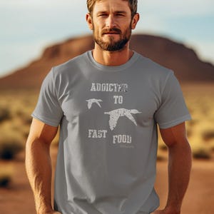 May include: A gray t-shirt with a white graphic that says "Addicted to Fast Food" with two stylized birds flying above the text.