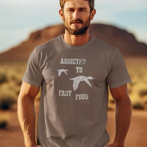 May include: A brown t-shirt with a white graphic that says "Addicted to Fast Food" with two stylized birds flying above the text.