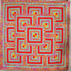 以下が含まれることがあります： 幾何学模様のカラフルなキルト。キルトは、ターコイズで縁取られた赤色の正方形と長方形のパターンと、黄色のアクセントが特徴です。背景は、ピンク、オレンジ、黄色の花柄のミックスです。