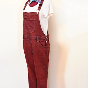 May include: A pair of red denim overalls with adjustable straps. The overalls have a classic fit and are made of a soft, comfortable fabric.