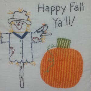 May include: Embroidered pillow with a scarecrow, pumpkin, and bird. The pillow has a white background with a red and green border. The text "Happy Fall Y'all!" is embroidered on the pillow.