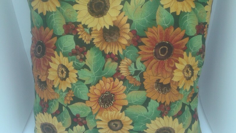 May include: A green and brown throw pillow with a floral pattern featuring sunflowers and leaves.