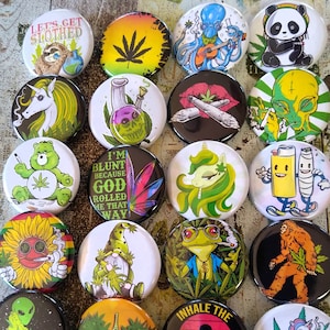 May include: A collection of round, colorful pinback buttons with various designs. The buttons feature illustrations of a sloth, panda, octopus, alien, unicorn, Care Bear, gnome, frog, Bigfoot, and more. Some buttons have text like "LET'S GET SLOTHED" and "INHALE THE GOOD SHIT EXHALE THE BULLSHIT".