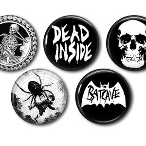 Pode incluir: Conjunto de cinco botões pretos e brancos. Os designs incluem um esqueleto, uma caveira, uma aranha e os textos "DEAD INSIDE" e "THE BATCAVE". Perfeitos para adicionar um toque gótico a qualquer roupa ou acessório.
