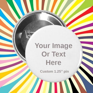 May include: White custom pin with the text "Your Image Or Text Here" and "Custom 1.25" pin". The pin is shown with its back side, revealing a safety pin clasp. The background features a colorful, radial pattern.