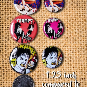 May include: A collection of six round pinback buttons with various designs. The buttons feature images of women, the band "The Cramps", and text. The size is 1.25 inches compared to 1 inch pin face.