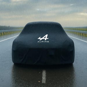 Könnte beinhalten: Eine schwarze Autoabdeckung mit dem weißen Alpine-Logo und der Zahl 4 auf einer nassen Straße. Das Auto ist abgedeckt, und das Bild wird im Regen aufgenommen. Der Hintergrund zeigt eine Autobahn und einen bewölkten Himmel.