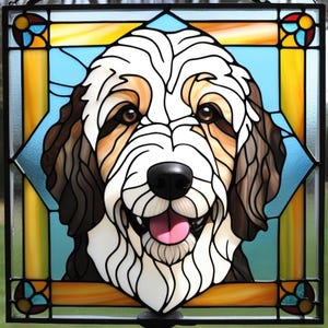May include: Stained glass window featuring a close-up portrait of a dog with brown, white, and tan fur. The dog has a happy expression with its tongue sticking out. The background is a light blue color with a yellow and orange border.
