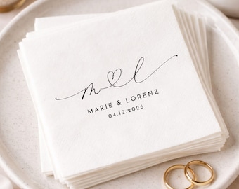 May include: A stack of square white paper napkins featuring black printed text that reads MARIE & LORENZ and the date 04.12.2026, with a stylized script monogram of the letters M and L connected by a heart symbol centered above the names.