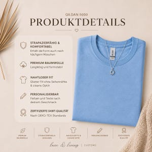 May include: A light blue Gildan 5000 t-shirt with a crew neckline and a silver sun pendant necklace. The image includes text detailing product features such as durability, premium cotton, seamless fit, and OEKO-TEX certification standards.