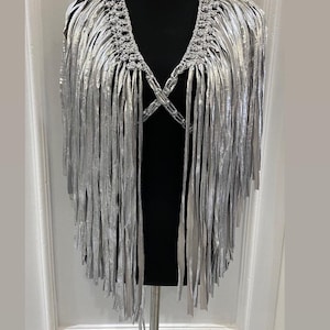 May include: A silver fringe collar necklace with a crocheted design. The fringe is long and flowing, and the collar is adjustable.