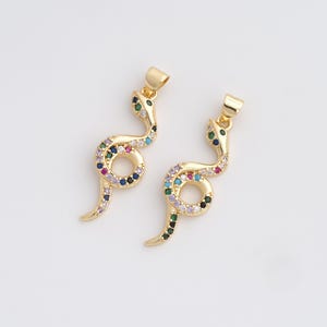 Peut inclure: Deux pendentifs dorés en forme de serpent avec des accents de pierres précieuses colorées. Les pendentifs serpent ont un design incurvé avec une boucle au milieu et une petite boucle en haut pour suspendre. Les pierres précieuses sont de différentes couleurs.