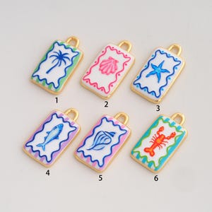 May include: Six rectangular metal charms with gold-tone edges and white enamel centers. Each charm features a unique colorful design: a palm tree, a pink shell, a blue starfish, a blue fish, a blue conch shell, and a red lobster, labeled 1 through 6.