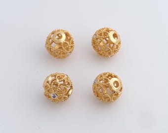 Peut inclure: Quatre perles dorées en filigrane avec des motifs ajourés complexes. Chaque perle comporte un petit cristal clair. Les perles sphériques sont probablement en métal, pour la fabrication de bijoux.