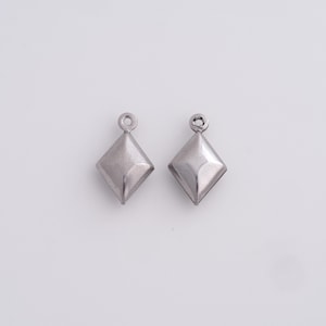 May include: Two silver-colored, diamond-shaped charms with a small loop at the top for hanging. The charms have a slightly textured surface and are displayed against a white background. These are suitable for jewelry making.