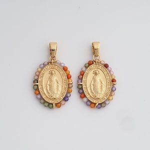 Peut inclure: Deux pendentifs ovales dorés représentant une figure religieuse, entourés d'une bordure perlée de différentes couleurs. Les pendentifs ont une boucle en haut pour être suspendus.
