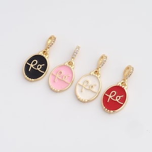 May include: Four gold-colored pendants with oval-shaped enamel centers. Each pendant has a different color: black, pink, white, and red. The word "fé" is written in cursive on each pendant. The pendants have a small loop with clear stones.