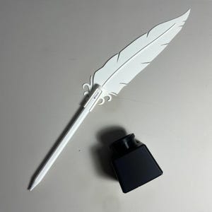 May include: A white plastic quill pen with a black ink bottle. The pen has a white plastic feather design and the words "Pencil" printed on the side.