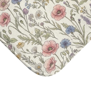 Könnte beinhalten: Blumenmuster auf cremefarbenem Hintergrund mit rosa Mohnblumen, blauen Kornblumen, Gänseblümchen und anderen Wildblumen. Das Design hat eine Vintage-Ästhetik mit handgezeichneten, zarten Linien und sanften Farben. Das Thema ist Natur und Botanik.